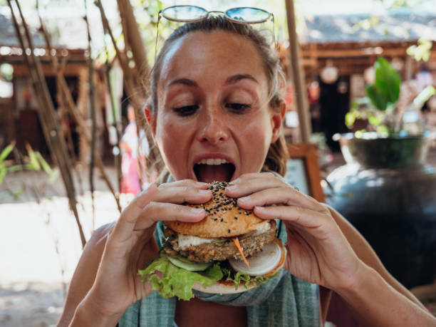 istock Woman eating vegan burger in cool cafe 1278982909