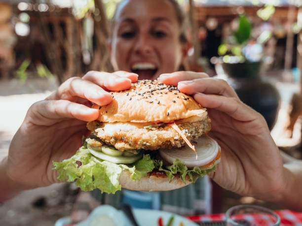 istock Woman eating vegan burger in cool cafe 1278982977