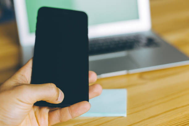 istock Hand using smartphone at office desk with laptop and stickers. 1278983163