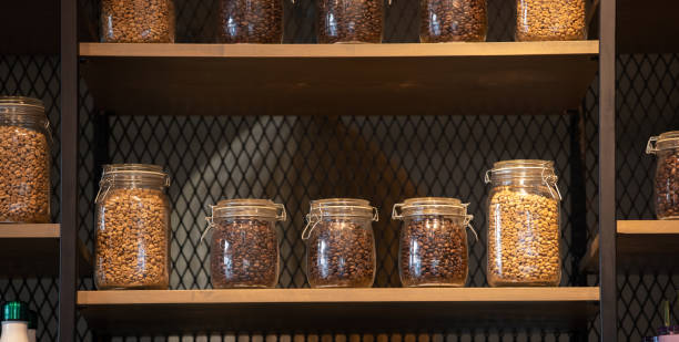 Brewing Coffee at Home - Coffee beans in a canister.\nTaken in natural light. Wooden table.