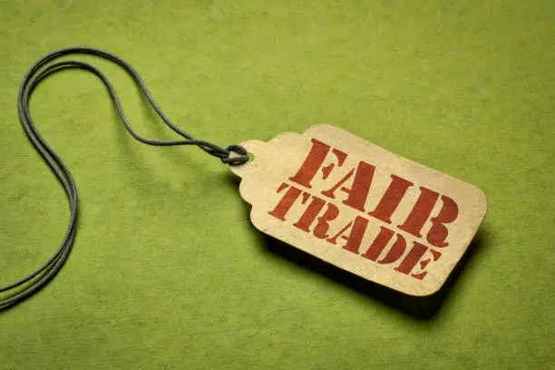 fair trade sign a paper price tag against green background - conscious shopping concept