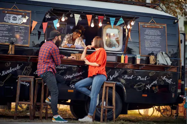 Hipster couple ordering from food truck on the street; Urban lifestyle concept