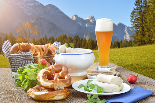Hearty Bavarian breakfast with veal sausages, fresh pretzels and a wheat beer outside in the nature near Garmisch-Partenkirchen