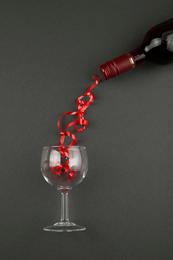 Glass curly ribbon and wine bottle on black background
