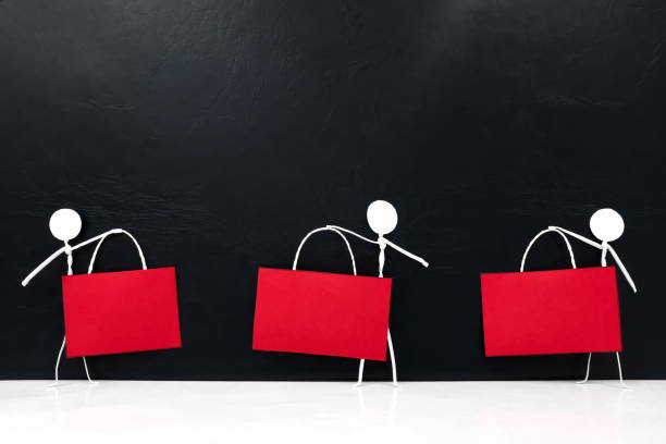 istock Stick man figure holding blank red signage template in dark background with copy space. Black friday sale and discount sign tag. 1278990036