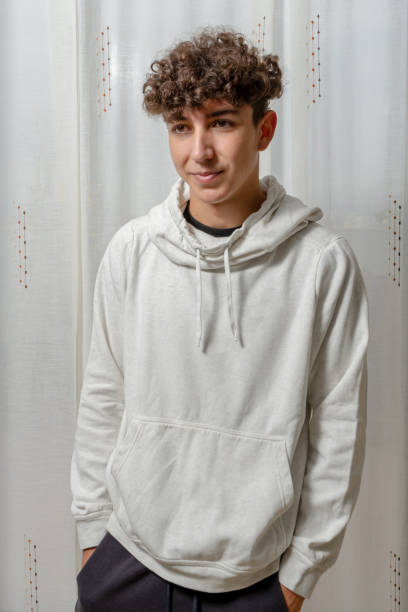 istock Attractive young man with curly hair wearing gray sweatshirt posing on white curtains background 1278993467
