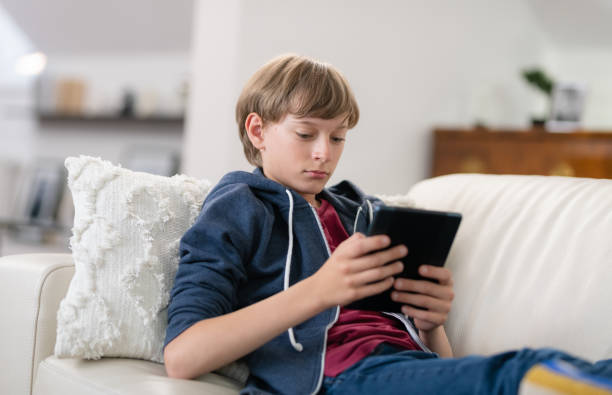 istock Young Boy Sitting In Living Room And Using Digital Tablet 1278993507