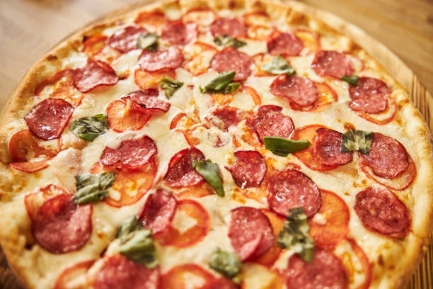 Close up of delicious pizza with salami, cheese, tomatoes and basil