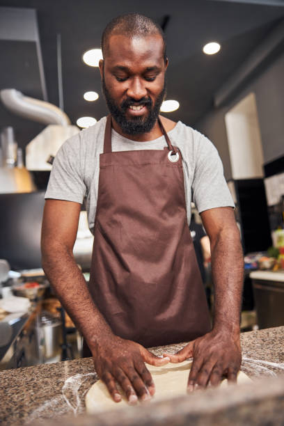 istock Cheerful young man making pizza in cafe 1278994646