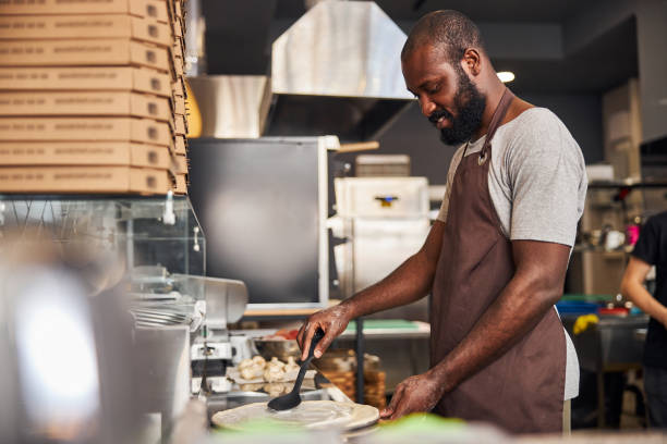istock Smiling handsome man cooking pizza in restaurant 1278994656