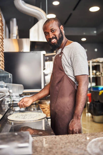 istock Cheerful young cooker making pizza in restaurant 1278994660