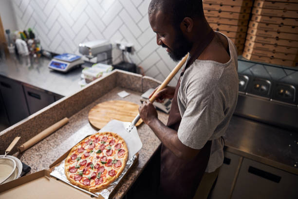 istock Handsome young man placing pepperoni pizza in paper box 1278994721
