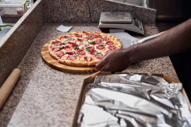 istock Young man placing pepperoni pizza on metal peel 1278994726
