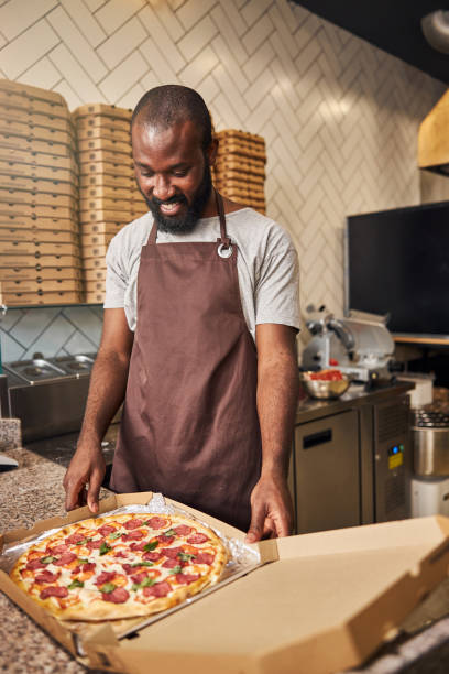 istock Handsome Afro American man standing at the counter with pizza 1278994730