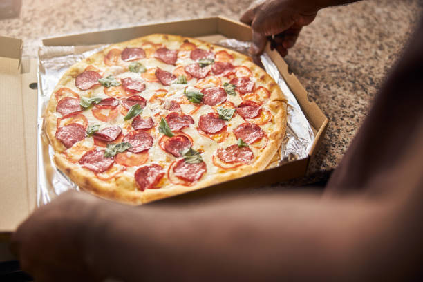 istock Young man holding cardboard box with pizza 1278994731