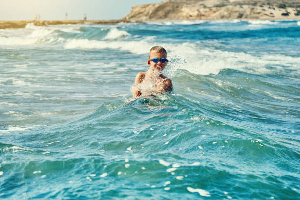 istock Boy in swimming glasses playing with sea waves 1278995514