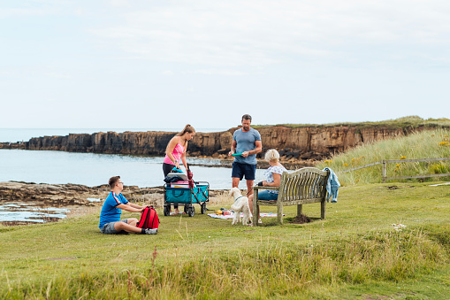 Single Hispanic man lifestyle portrait at beach sitting on headland at Skrinkle Haven on the Pembrokeshire Coast with his dog