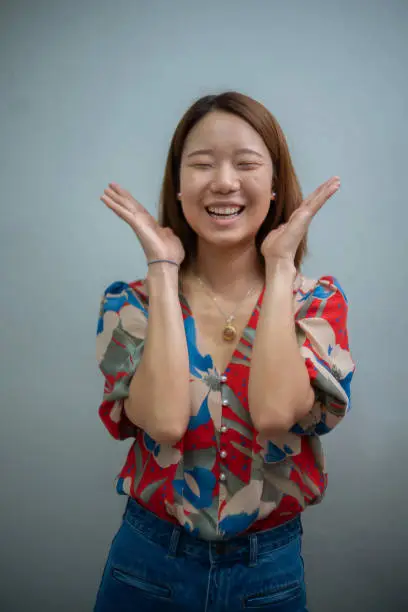 Cheerful Asian woman before makeup smile and liftup hands over face.