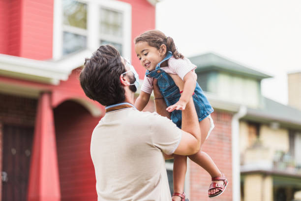 istock Dad, wearing mask, holds daughter up in air 1278998285