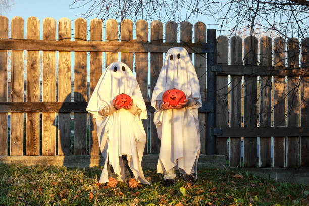 istock kids in ghost costume with pumpkins in sunlight 1278998638