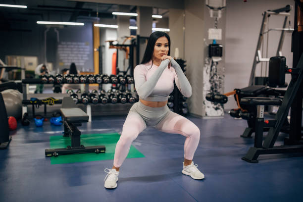 istock One young attractive fit brunette doing squats in the gym 1278998907