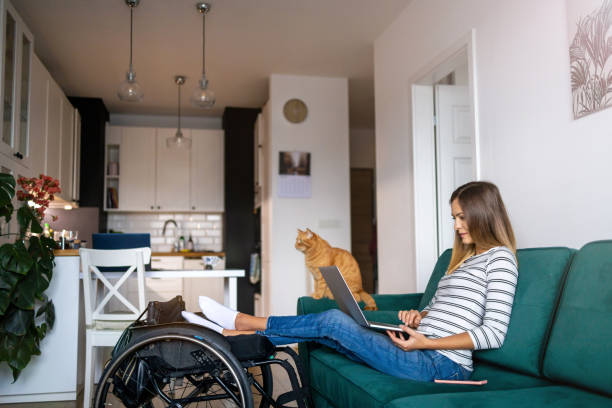 istock Disabled young woman using laptop while sitting on sofa at home 1279000195