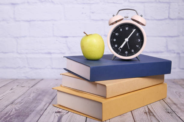istock black to school concept with apple and clock on stack of books 1279001547