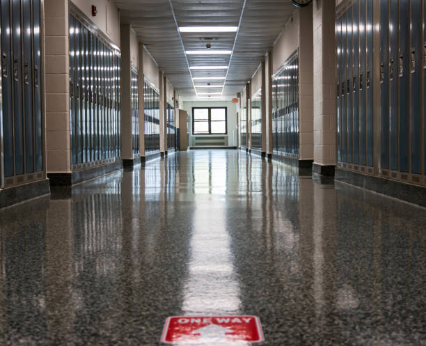 両側にロッカーがあり、パンデミックのために床に一方通行がマークされた高校の廊下 - hall way ストックフォトと画像
