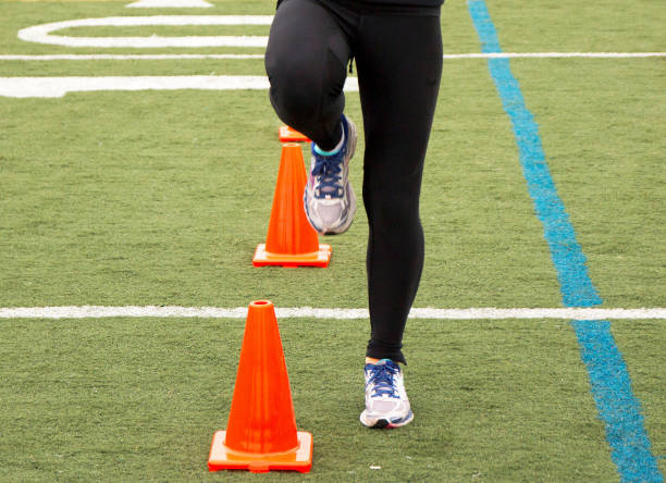 istock Runner in black spandex tights stepping over orange cones on a turf field 1279002924