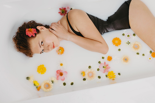 An attractive girl relaxing in bath with flowers. Spa, personal care, beauty salon, relaxation on resort.