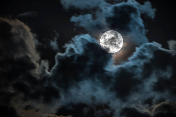 istock Full moon in between the clouds and idyllic scenery. Amazing the moon rough surface with craters from meteorites from the universe that crash our satellite the Moon an awe relief lunar map 1279008479