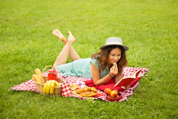 istock Young woman reading a book in the park 1279009998