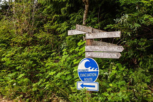 Signs in Bamfield direct walkers to local landmarks and nearby roads in West Bamfield, ontop of a Tsunami Warning sign.