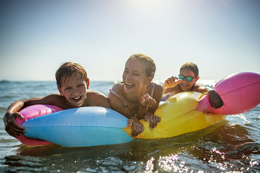 Brothers and sister having fun on air mattress in the sea. Kids are laughing and enjoying the vacations.
Nikon D850