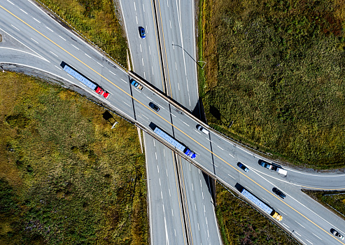 Looking down on a trio of semi trucks on a highway overpass.