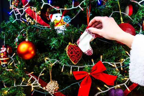 istock Decorating Christmas tree, hand putting Christmas decorations on fir branches. Christmas hanging decorations. 1279011317