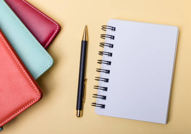 istock Multi-colored diaries lie on a beige background near a blank notebook and a pen. Flat lay. Copy space 1279014730