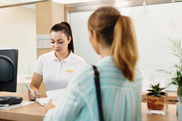 istock Female receptionist filling paperwork while talking to a customer at the spa. 1279015132