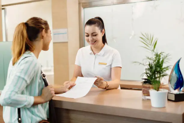 Photo of Happy receptionist talking to a customer at health spa.