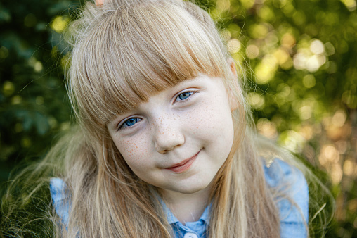 charming little girl with blue eyes and long Golden hair is smiling. Happy funny child.