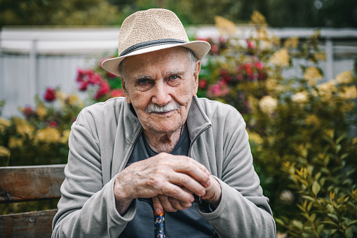 Portrait of a smiling and confident older 87-year-old handsome man in a hat with a mustache. Happy active old age. Portrait of a man in the autumn.