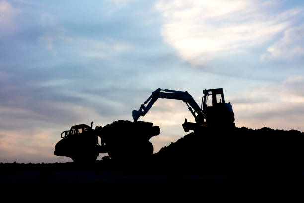 istock Mini Excavator loading dumper truck ot sunset 1279016679