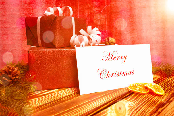 two christmas presents on a wooden table with a greeting card