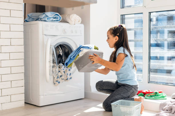 istock Beautiful child girl little helper is having fun and playing while doing laundry at home. 1279032727