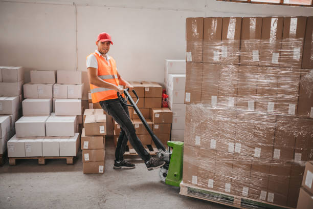 istock Warehouse worker standing among shelves with handcart 1279035372