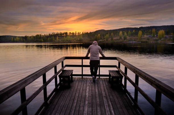 mężczyzna stoi na molo i wychodzi na morze, zachód słońca i las w jesiennych kolorach - norrland zdjęcia i obrazy z banku zdjęć