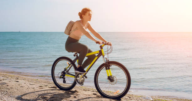 istock Young woman bicycling along a beach 1279040458