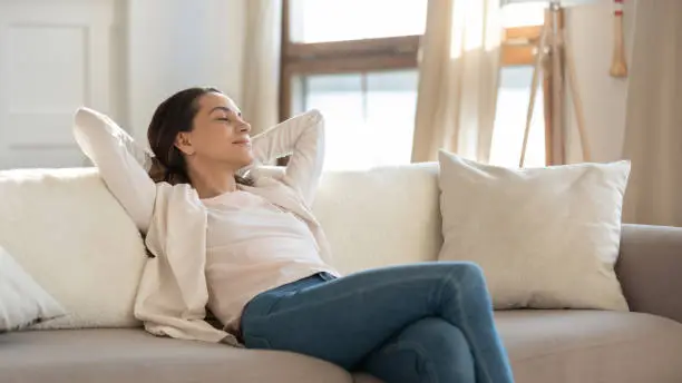 Photo of Confident millennial female enjoying tranquility relaxing on sofa indoors