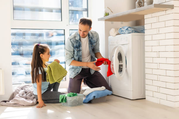 istock Happy Family loading clothes into washing machine in home 1279044812