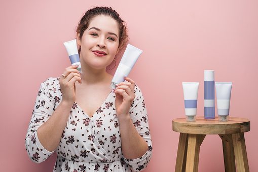 A young latin woman wearing makeup and showing beauty products to the camera.